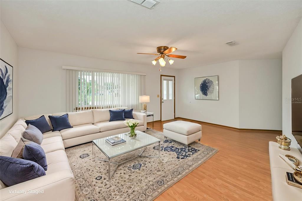 A living room features a large white sectional sofa, a glass coffee table, and wood flooring — 9881 SW 101ST PLACE, OCALA, FL