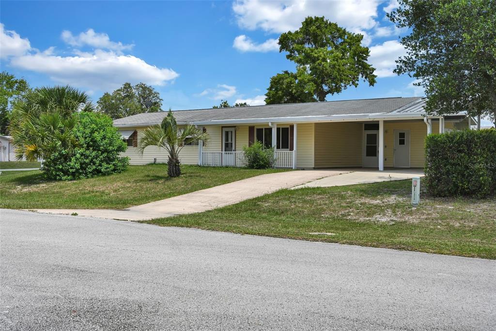 A single-story yellow house with a concrete driveway and a covered carport — 9881 SW 101ST PLACE, OCALA, FL