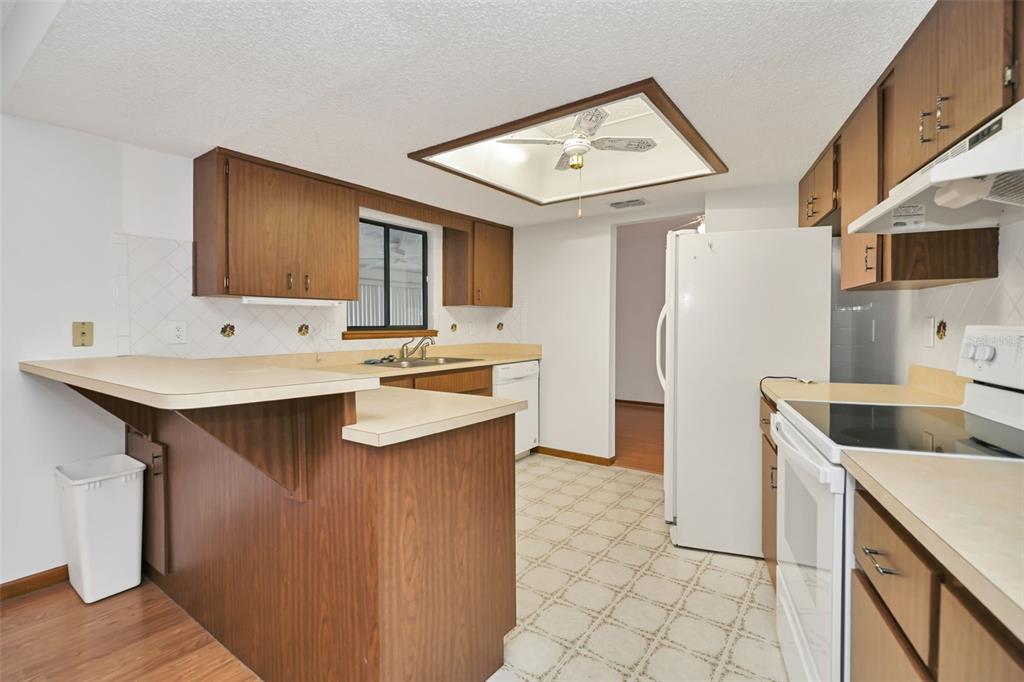 A kitchen features wood cabinets, laminate countertops, a white refrigerator, and a ceiling fan — 9881 SW 101ST PLACE, OCALA, FL