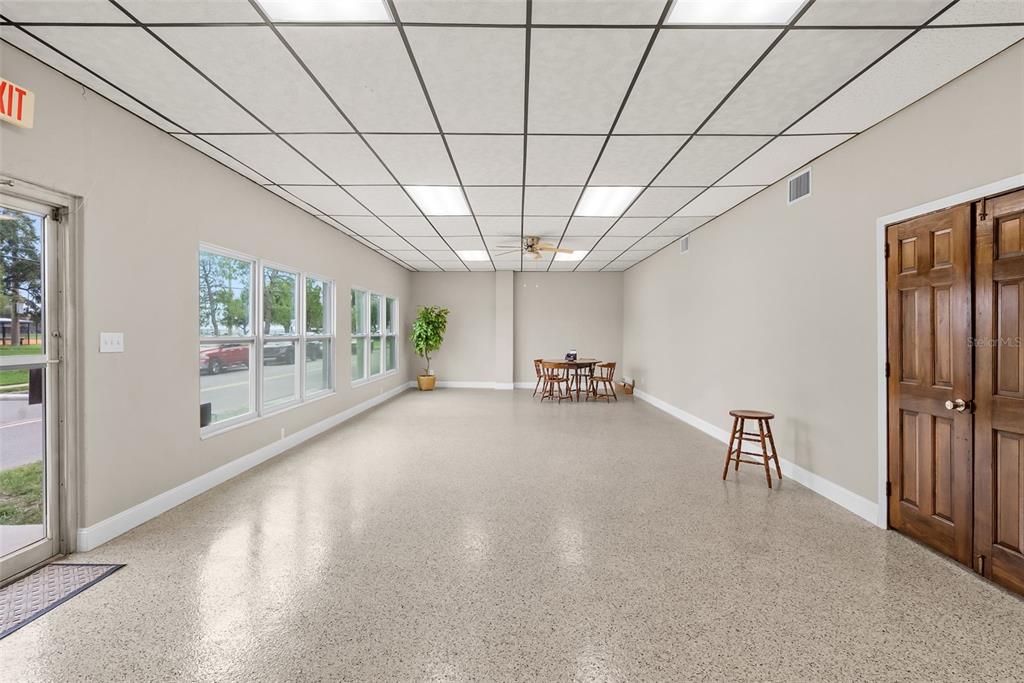 A spacious room features a drop ceiling, light-colored walls, a speckled floor, and a small table — 1444 19TH STREET N, ST PETERSBURG, FL