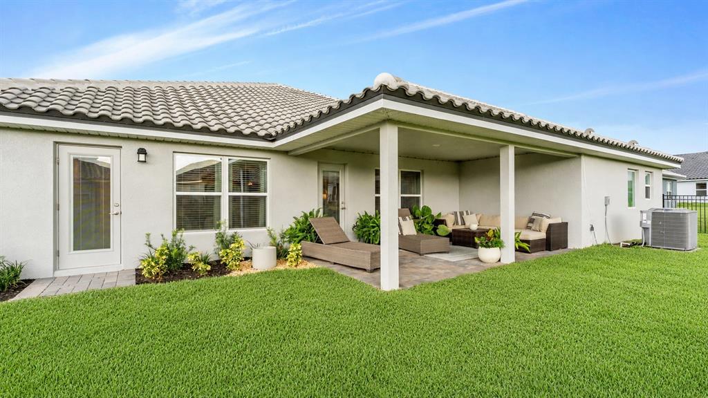 A house exterior features a covered patio with outdoor furniture and a grassy backyard — 5280 TENNESSEE RIDGE COURT, AUBURNDALE, FL