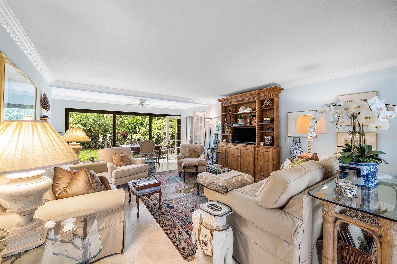 A living room features beige sofas, a wooden entertainment center, and a view of greenery — 4233 A Quail Ridge Drive N, Boynton Beach FL 33436, BOYNTON BEACH, FL