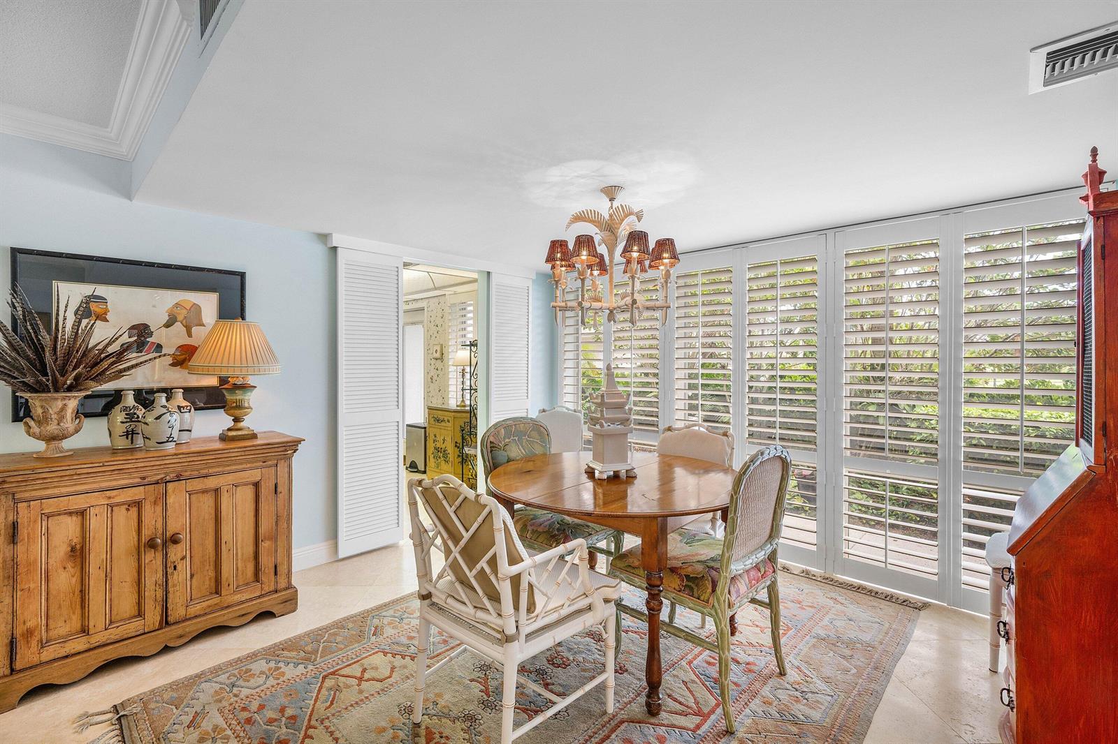 A dining room features a round wooden table, white bamboo chairs, and plantation shutters — 4233 A Quail Ridge Drive N, Boynton Beach FL 33436, BOYNTON BEACH, FL