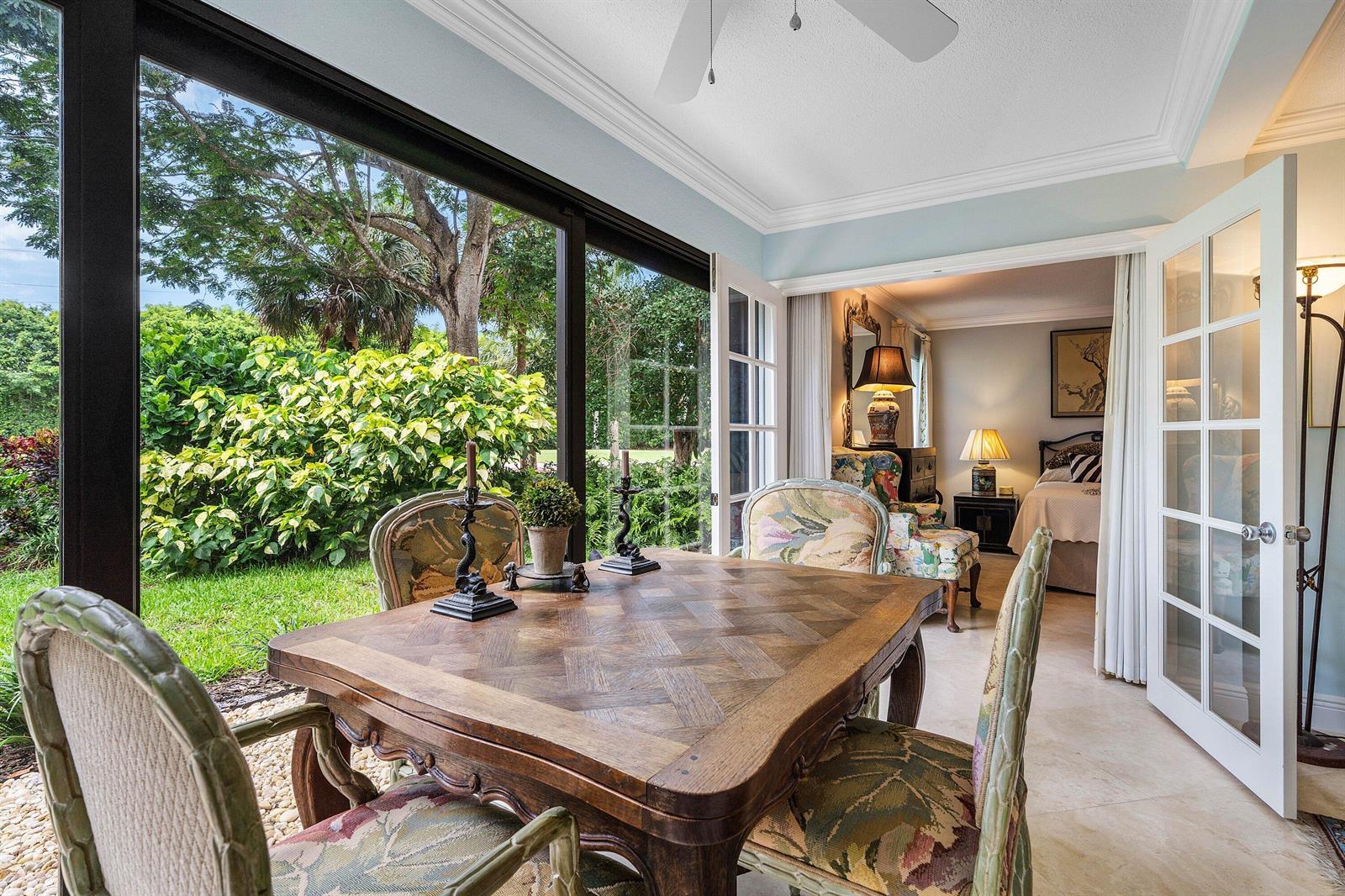 A dining area with a wooden table overlooks a lush backyard through large glass windows — 4233 A Quail Ridge Drive N, Boynton Beach FL 33436, BOYNTON BEACH, FL