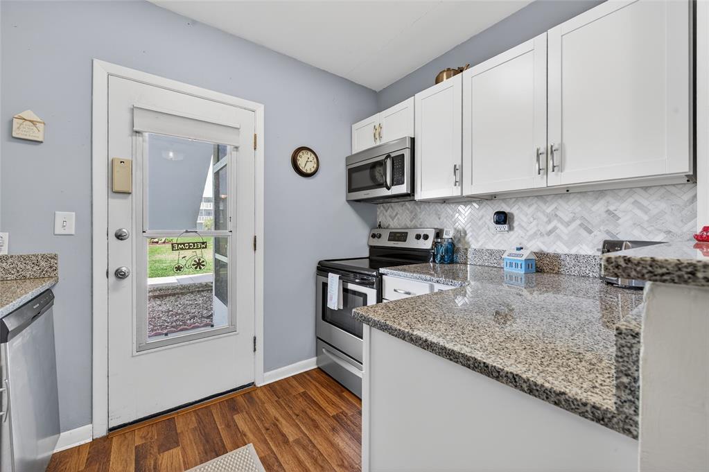 A kitchen features white cabinets, granite countertops, stainless steel appliances, and a glass-paneled exterior door — 3009 N HALIFAX AVENUE UNIT 1, DAYTONA BEACH, FL
