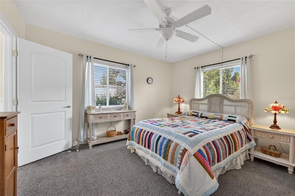 A bedroom features a bed with a colorful quilt, two windows, and a ceiling fan — 3009 N HALIFAX AVENUE UNIT 1, DAYTONA BEACH, FL