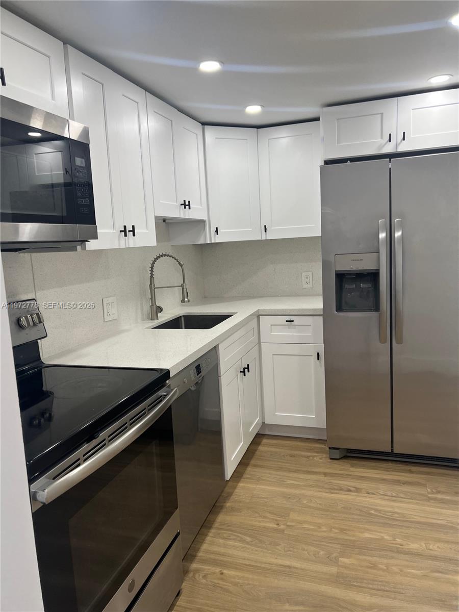 A kitchen features white shaker cabinets, stainless steel appliances, and light-colored countertops — AVENTURA, FL