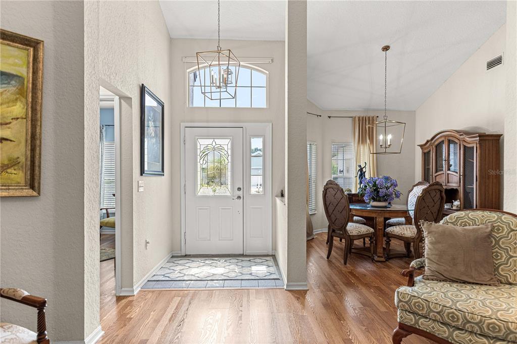 A bright entryway with hardwood floors, a white front door, and an adjacent dining area — 11606 SW 75TH CIRCLE, OCALA, FL