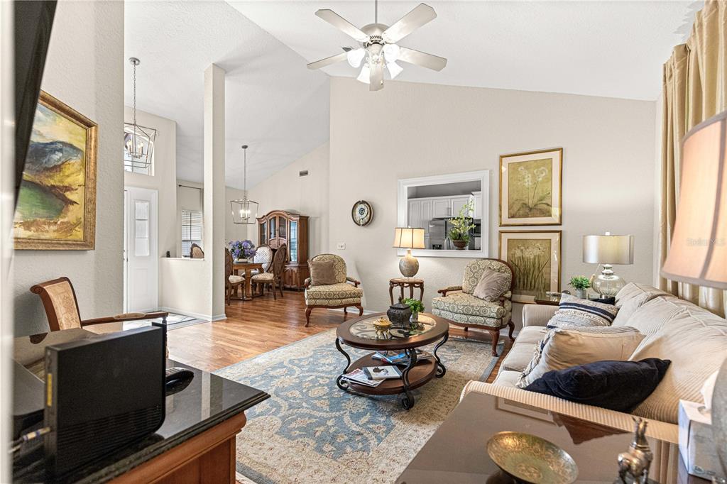 A living room with vaulted ceilings, hardwood floors, a ceiling fan, and an area rug — 11606 SW 75TH CIRCLE, OCALA, FL