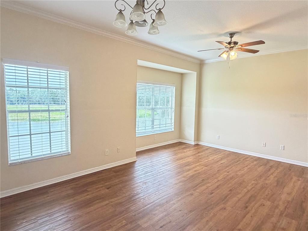 An empty room with wood-look flooring, two windows, a ceiling fan, and a light fixture — 407 EAGLE POND DRIVE UNIT 407, WINTER HAVEN, FL