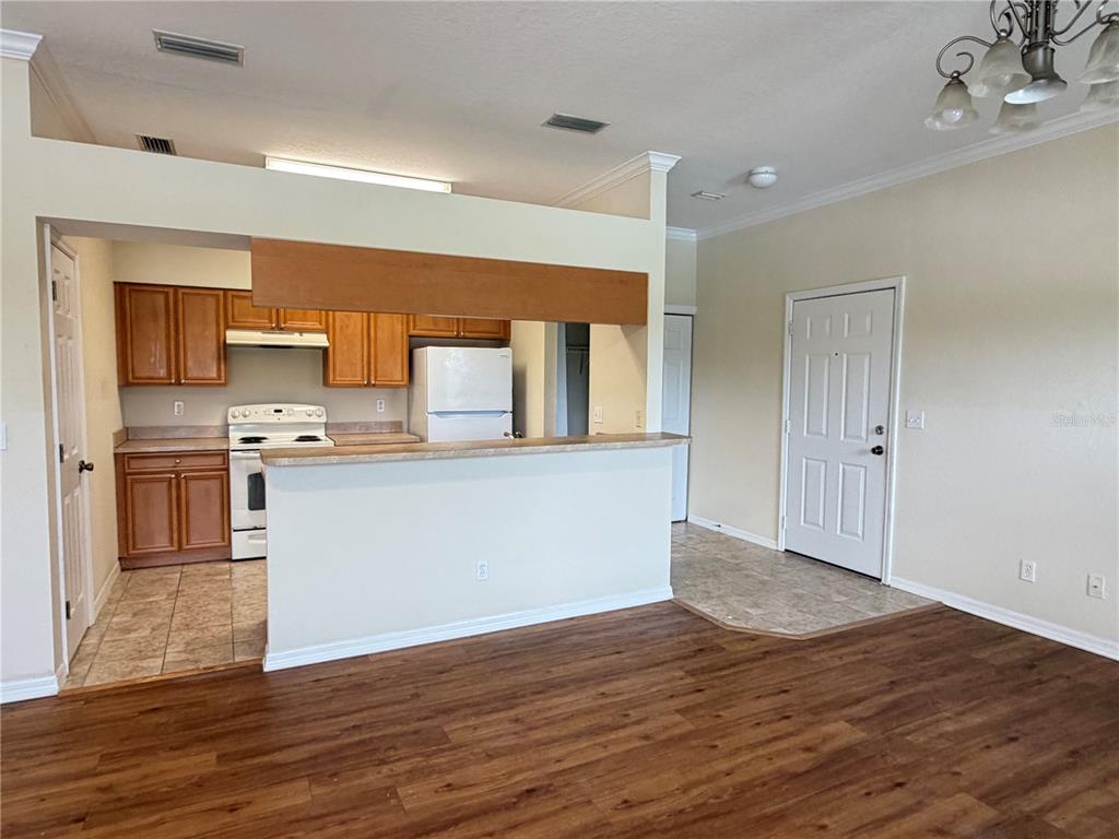 A kitchen with wood cabinets and a breakfast bar overlooks a living area with flooring — 407 EAGLE POND DRIVE UNIT 407, WINTER HAVEN, FL