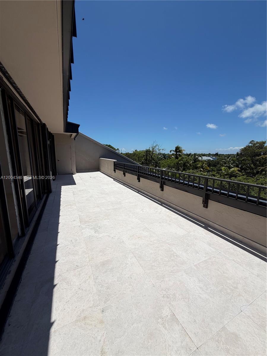 A spacious outdoor balcony features light-colored stone tile flooring and a black metal railing — 151 Crandon Blvd # 444, Key Biscayne FL 33149, KEY BISCAYNE, FL