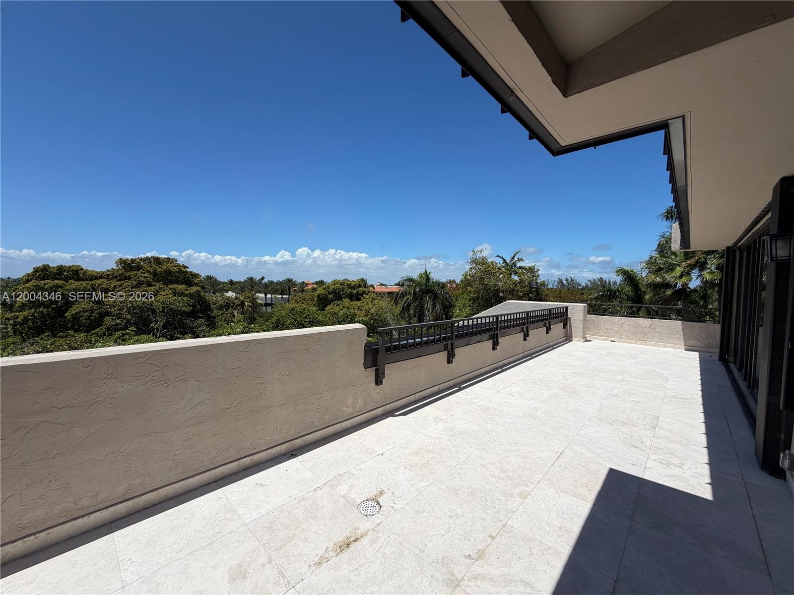 A spacious outdoor balcony features light-colored tile flooring, a stucco wall, and metal railings — 151 Crandon Blvd # 444, Key Biscayne FL 33149, KEY BISCAYNE, FL