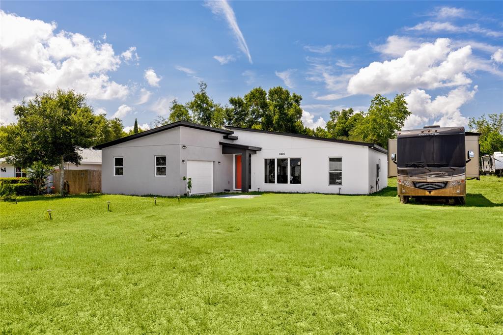 A modern, single-story house with a white and gray exterior sits on a grassy lot — 11426 LAKEVIEW DRIVE, LEESBURG, FL