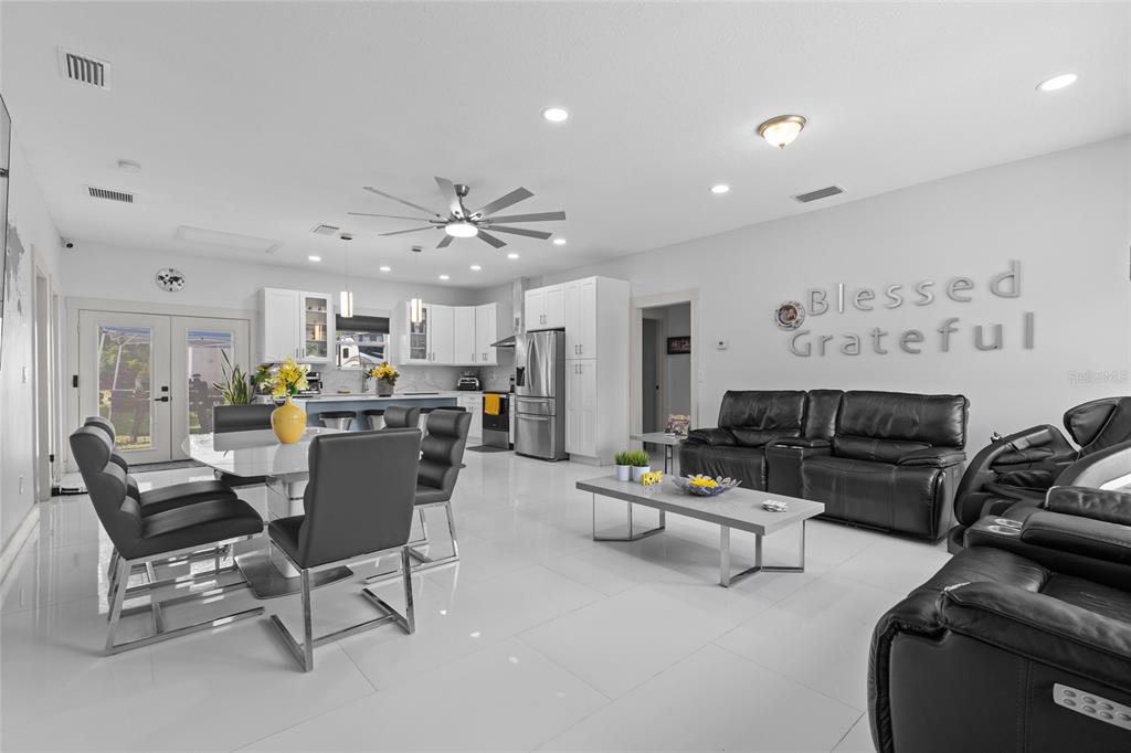 An open-concept kitchen and living area features white tile floors and black leather furniture — 11426 LAKEVIEW DRIVE, LEESBURG, FL