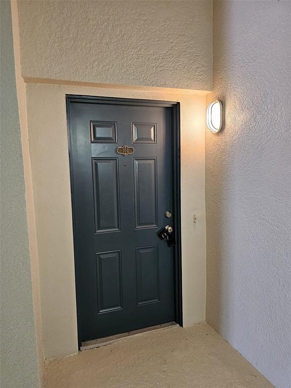 A dark blue front door with a lockbox is set into a beige exterior wall — 3321 WHITESTONE CIRCLE UNIT 102, KISSIMMEE, FL