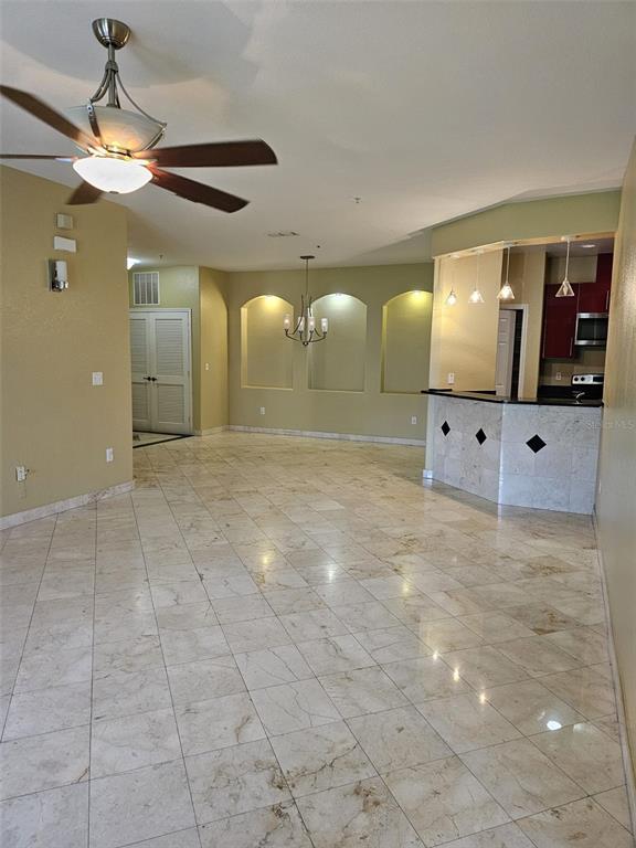 An open-concept living area features light-colored tile flooring, a ceiling fan, and a kitchen bar — 3321 WHITESTONE CIRCLE UNIT 102, KISSIMMEE, FL