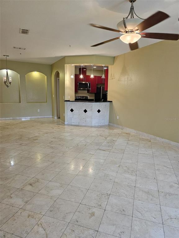 A spacious room with light-colored tile flooring, a kitchen breakfast bar, and a ceiling fan — 3321 WHITESTONE CIRCLE UNIT 102, KISSIMMEE, FL
