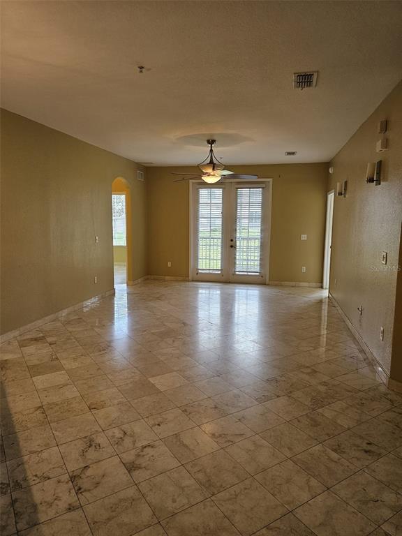 An empty room features light-colored tile flooring, a ceiling fan, and glass doors leading outside — 3321 WHITESTONE CIRCLE UNIT 102, KISSIMMEE, FL