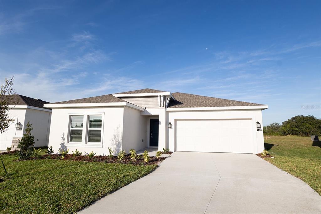 A single-story house with a white stucco exterior, a two-car garage, and a concrete driveway — 1482 AUSTIN STREET, WINTER HAVEN, FL