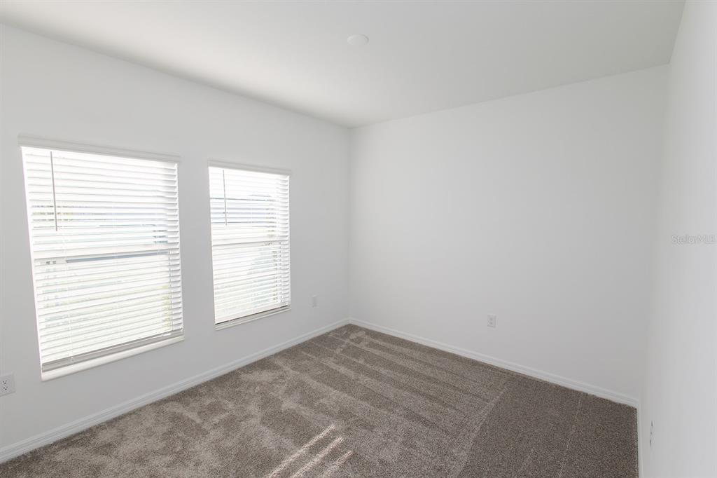 An empty bedroom features white walls, gray carpeting, and two windows with white blinds — 1482 AUSTIN STREET, WINTER HAVEN, FL