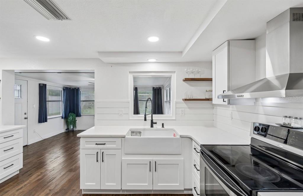 A kitchen with white cabinets, a farmhouse sink, and a stainless steel range hood — 4531 KENNEDY DRIVE, NEW PORT RICHEY, FL