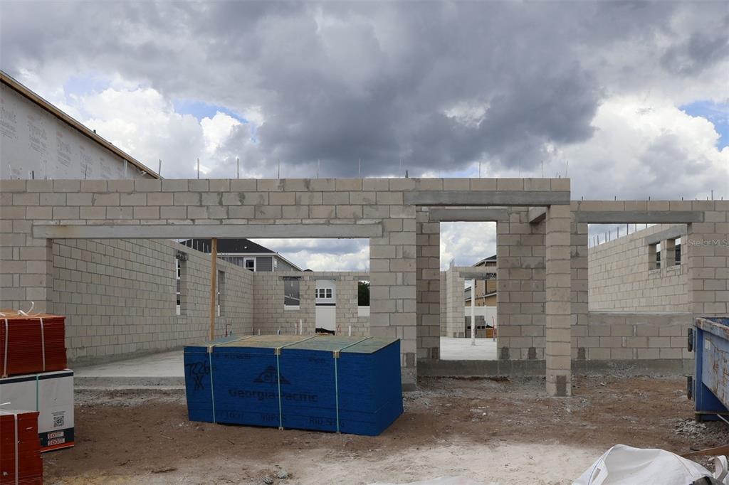 An unfinished room with exposed wooden wall studs, roof trusses, and stacks of drywall panels — 1136 BASALT LANE, SANFORD, FL