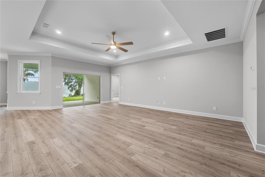 A long hallway with light wood-look flooring, white walls, and a tray ceiling — 4545 FAIRWAY OAKS DRIVE, MULBERRY, FL