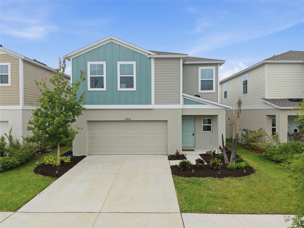 A two-story suburban house features a teal accent wall, a garage, and a front walkway — 12950 PASTURE WOODS PLACE, LITHIA, FL