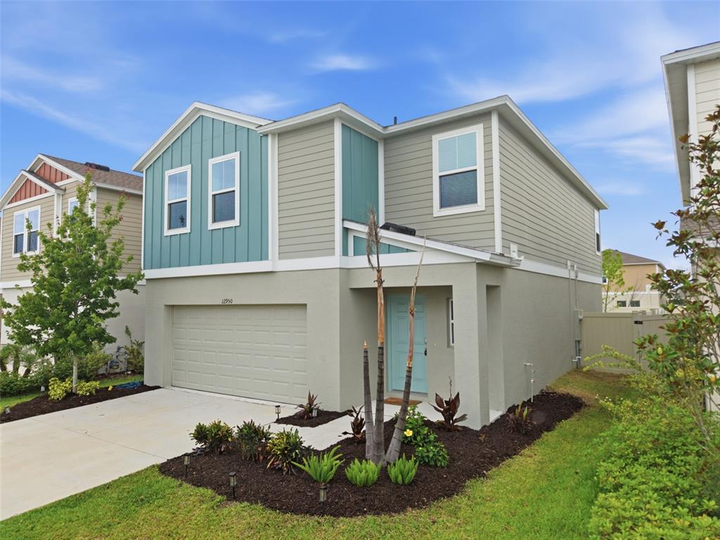 A two-story house with a light green stucco base, teal siding, and a two-car garage — 12950 PASTURE WOODS PLACE, LITHIA, FL