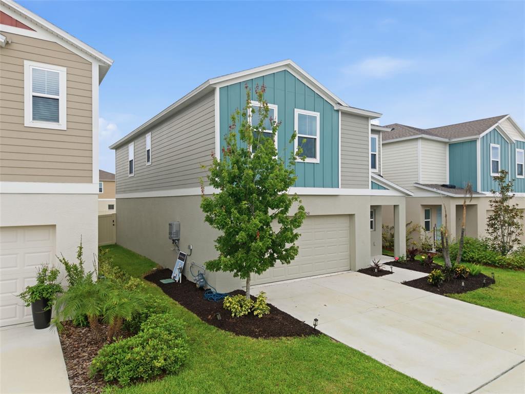 A two-story house with a teal and beige exterior features a front-facing garage and landscaping — 12950 PASTURE WOODS PLACE, LITHIA, FL