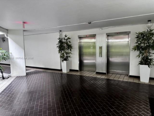 An indoor lobby area features two stainless steel elevators flanked by potted plants on tile — 13951 Kendale Lakes Cir # 807A, Miami FL 33183, MIAMI, FL