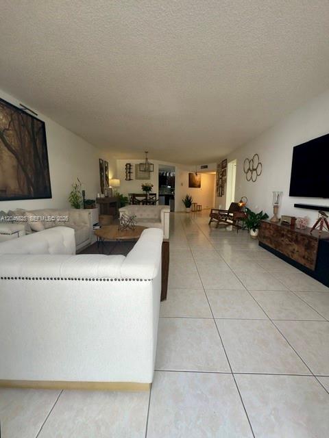 A living room features white tiled floors, a tufted sofa, and a wall-mounted television — 13951 Kendale Lakes Cir # 807A, Miami FL 33183, MIAMI, FL