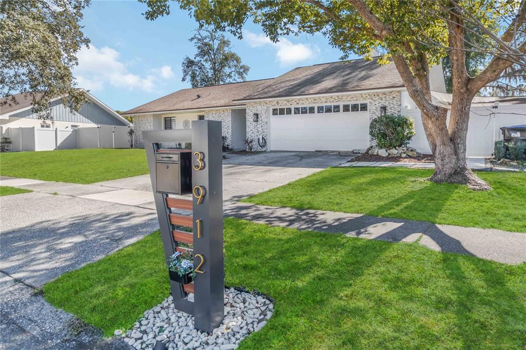 A modern, dark-colored mailbox stand with house numbers sits on a lawn before a house — 3912 CHERRY APPLE CIRCLE, ORLANDO, FL