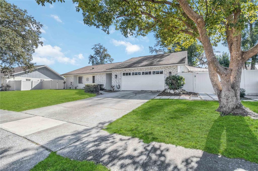 A single-story house with a white stone facade, a two-car garage, and a large tree — 3912 CHERRY APPLE CIRCLE, ORLANDO, FL