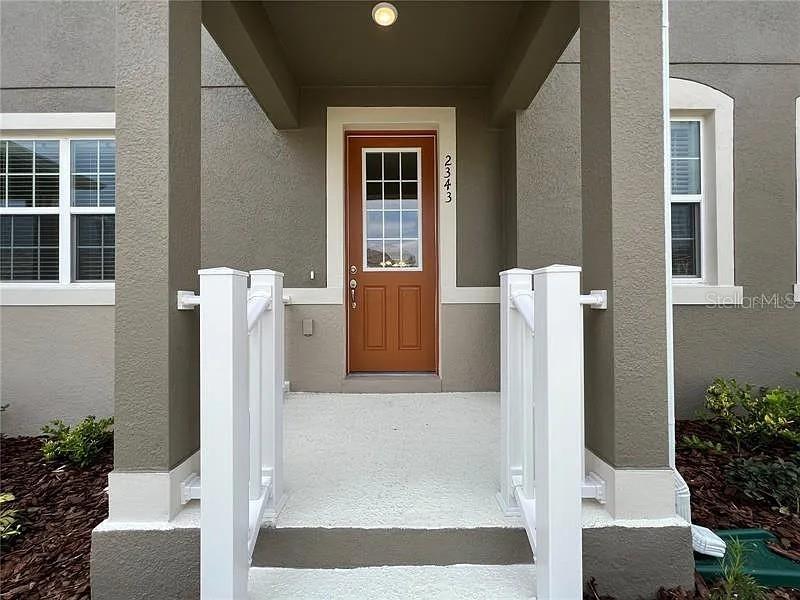 A front entryway features a brown door with a glass pane and white railings — 2343 GARDEN  BELLE DRIVE, CLERMONT, FL