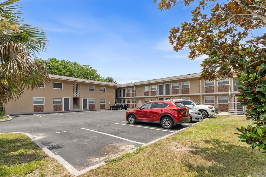 A two-story apartment building with a parking lot in front and a red SUV parked — 501 NW 15TH AVENUE UNIT 11, GAINESVILLE, FL