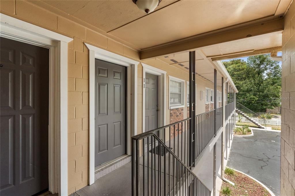 An exterior walkway with metal railings leads past several apartment doors at a multi-story building — 501 NW 15TH AVENUE UNIT 11, GAINESVILLE, FL