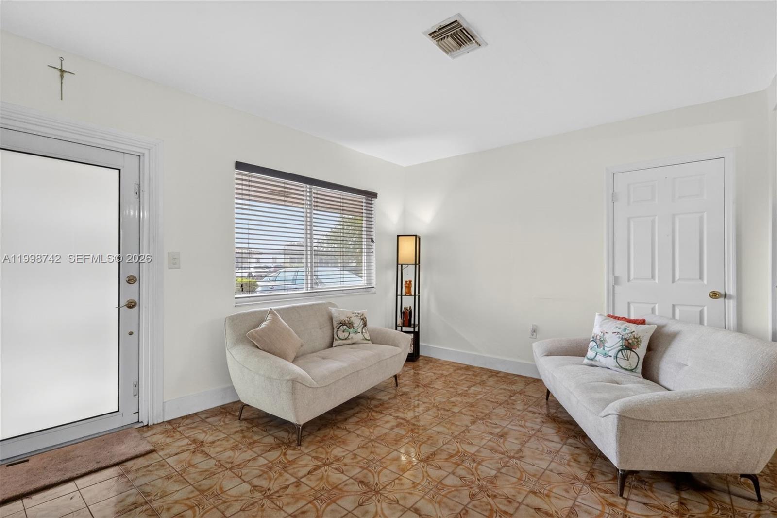 A living room features two light-colored sofas, a window with blinds, and tiled flooring — 733 W 33rd St, Hialeah FL 33012, HIALEAH, FL