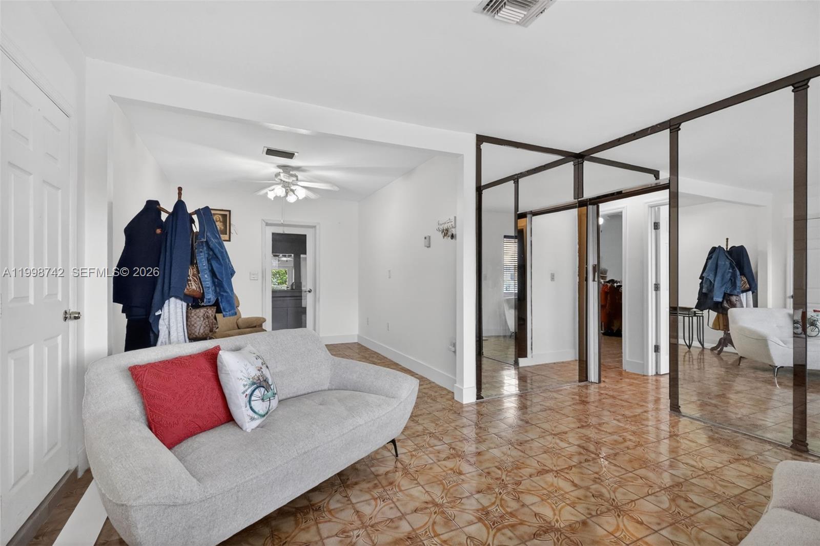 A living room features light gray furniture, patterned tile flooring, and large mirrored closet doors — 733 W 33rd St, Hialeah FL 33012, HIALEAH, FL