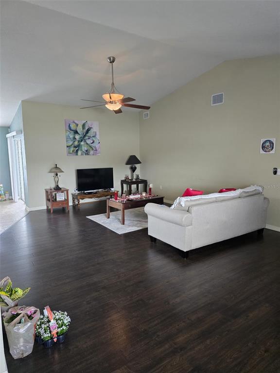 A living room features dark wood flooring, a vaulted ceiling, and a light-colored sofa — 2956 COACH LAMP ROAD, MULBERRY, FL