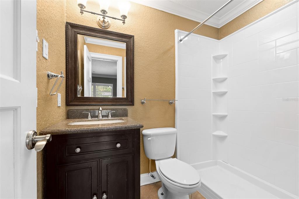 A bathroom features a dark wood vanity, a framed mirror, and a white shower stall — 229 FLAME AVENUE, MAITLAND, FL