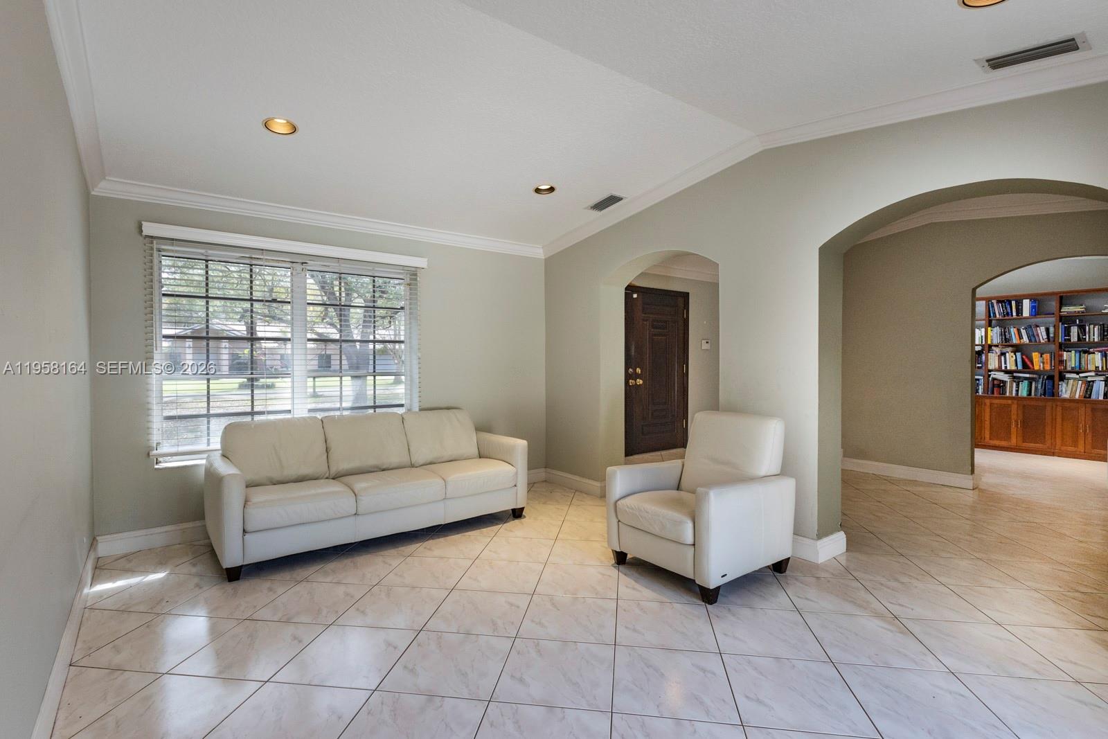 A living room features a white sofa, an armchair, tile flooring, and a built-in bookshelf — 7821 SW 129th Ter, Pinecrest FL 33156, PINECREST, FL