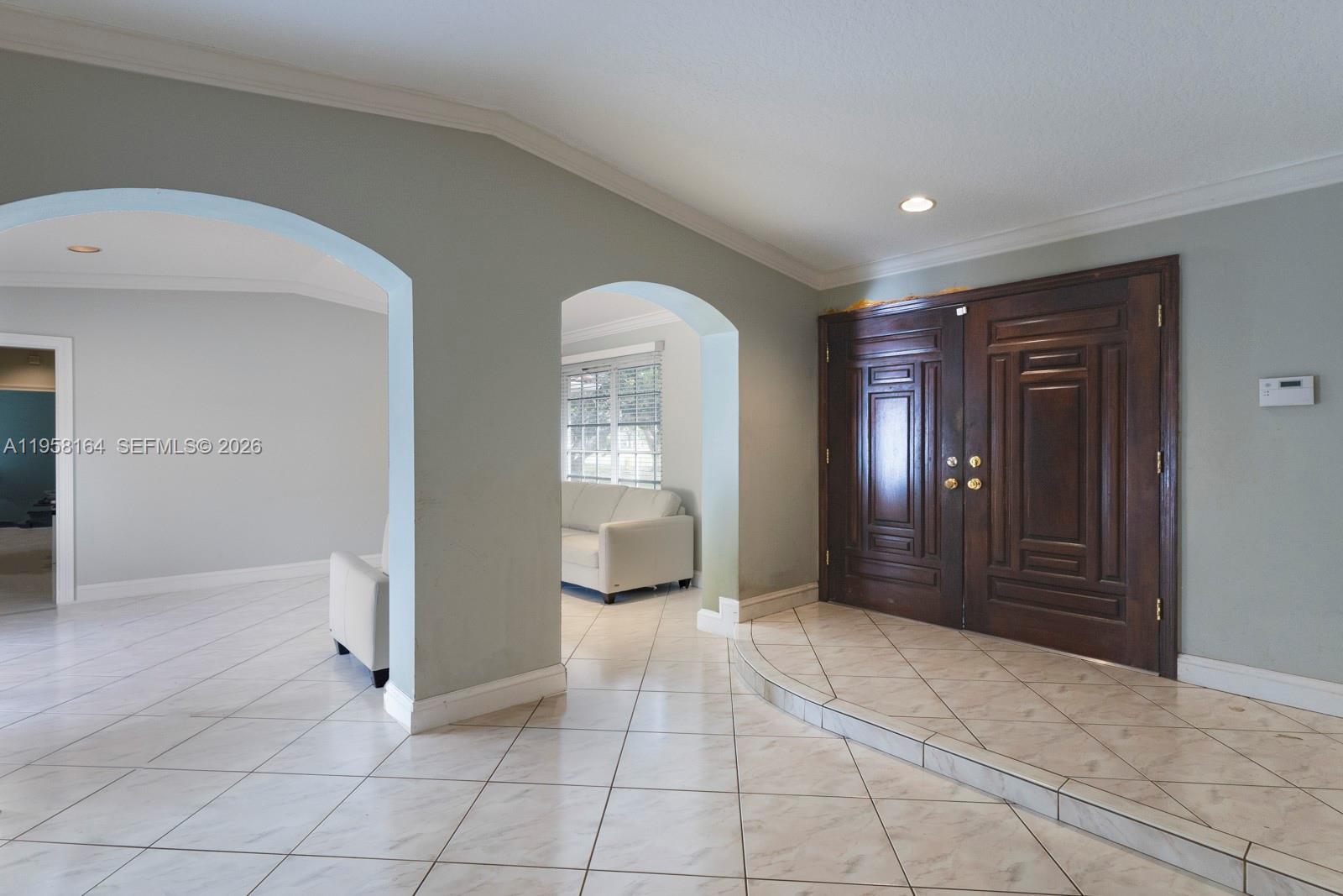 An entryway features a raised tiled landing, double wooden doors, and arched openings to adjacent rooms — 7821 SW 129th Ter, Pinecrest FL 33156, PINECREST, FL