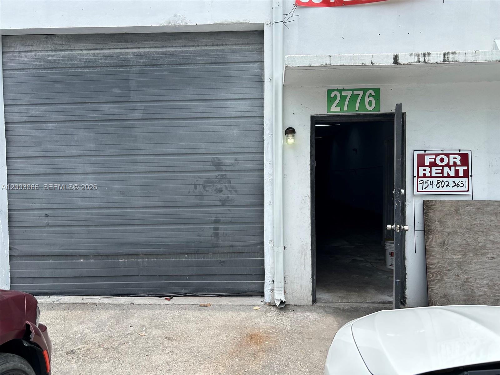 A commercial unit features a metal roll-up door and an open entrance door with signage — 2776 NW 21st Ter, Miami FL 33142, MIAMI, FL