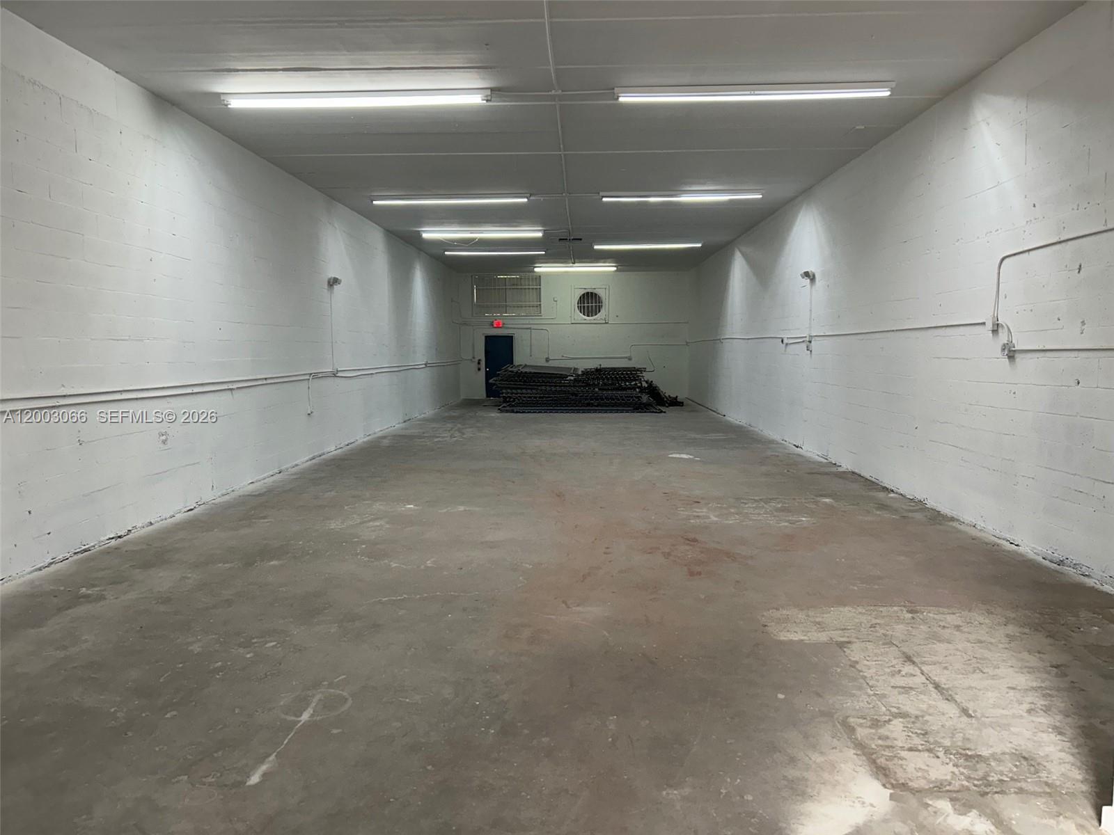An empty, rectangular warehouse space features white painted block walls, concrete floors, and overhead lighting — 2776 NW 21st Ter, Miami FL 33142, MIAMI, FL