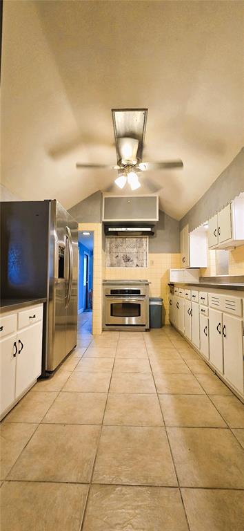 A galley kitchen features white cabinets, stainless steel appliances, and beige tile flooring — 240 MASTERPIECE ROAD, LAKE WALES, FL