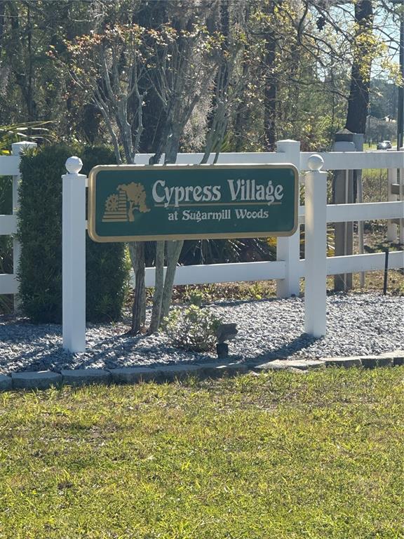 A green sign for Cypress Village at Sugarmill Woods stands behind a white fence — 7 SWEETBAY COURT, HOMOSASSA, FL