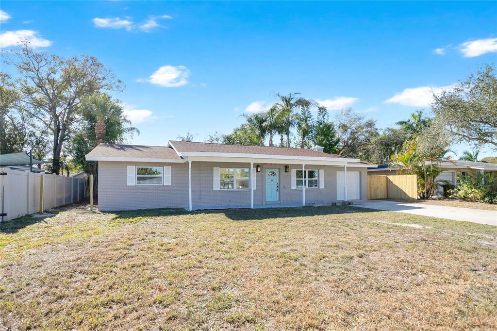 A single-story gray brick house features a light blue front door and a covered porch — 214 45TH AVENUE NE, ST PETERSBURG, FL