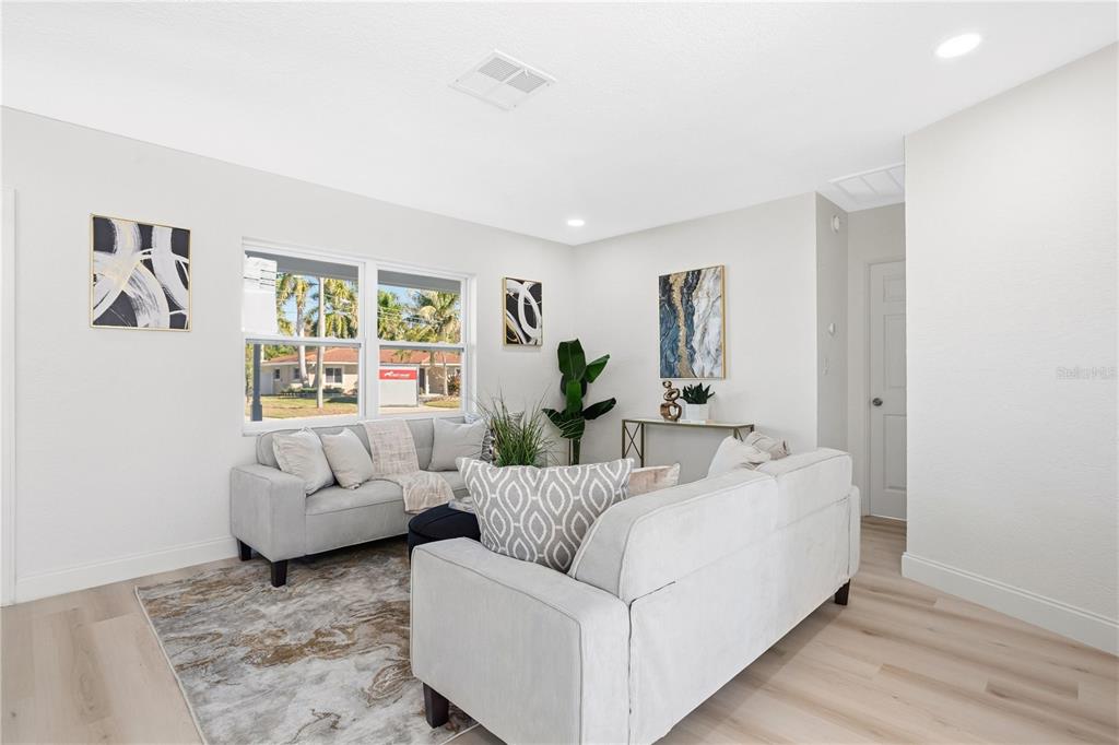 A living room features light-colored sofas, a patterned area rug, and modern wall art — 214 45TH AVENUE NE, ST PETERSBURG, FL